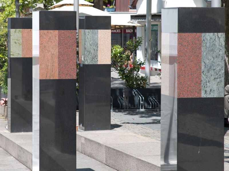 Renate Hoffleit, Stufenanlage mit 8 Türmen, 1994/2015 (Detail). Ansicht eines Details der Stufenanlage mit 8 Türmen von Renate Hoffleit. Auf verschieden hohen Stufen stehen vier Türme in verschiedenen Farben im Bild.