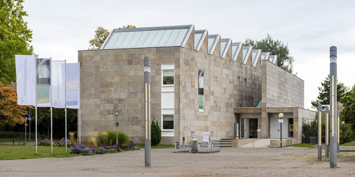 Das Museum im Kleihues-Bau vom Marktplatz aus. Foto: Frank Kleinbach. Außenansicht des Museums im Kleihues-Bau vom Marktplatz aus, links wehende Flaggen.